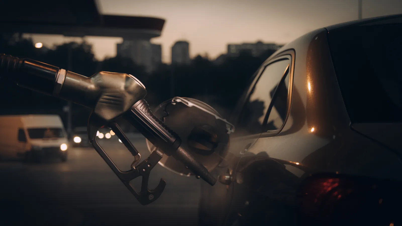 Conceptual editorial image of a gasoline pump beside a commuter car at a US filling station, illustrating fuel costs rather than a photographed news event.